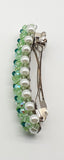 Green beaded flower pattern hair barrette on a white pearl base.