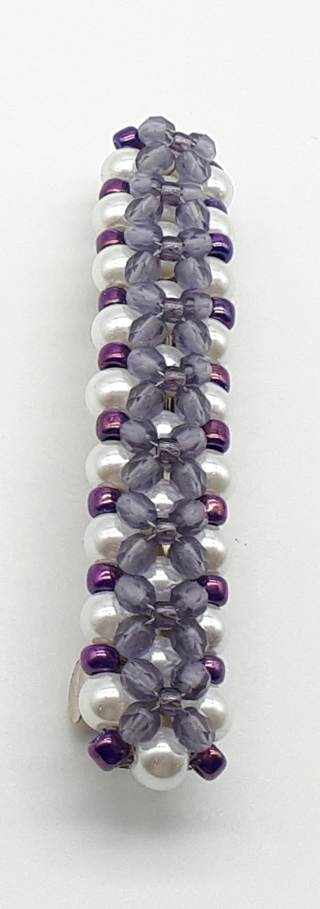 Purple beaded flower pattern hair barrette on a white pearl base.